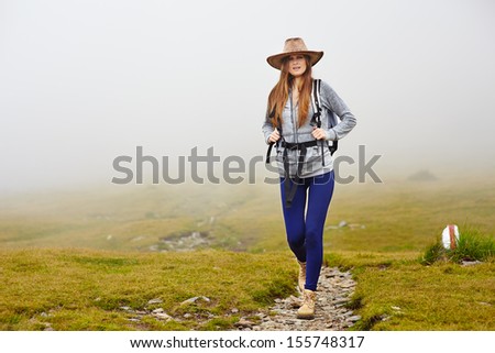 Female hiker with backpack and hat on a mountain trail