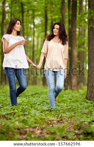 Mother and daughter walking hand in hand through a forest and talking
