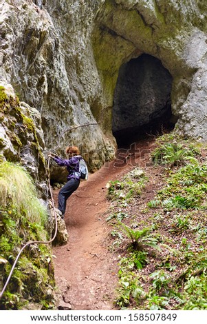 Woman getting out from a cave holding on to a safety cable