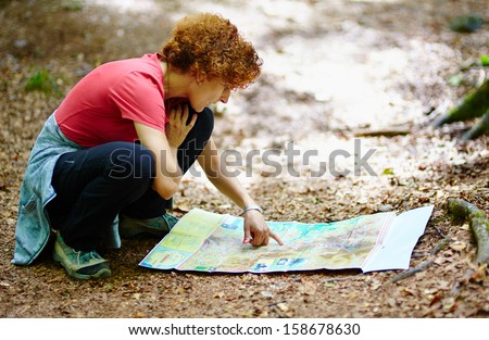 Female tourist looking on a map in a forest