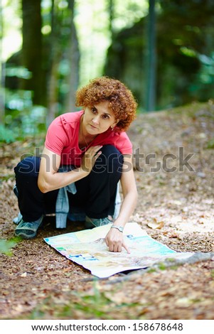 Female tourist looking on a map in a forest
