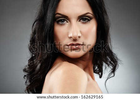 Closeup portrait of sensual brunette looking over the shoulder over gray background
