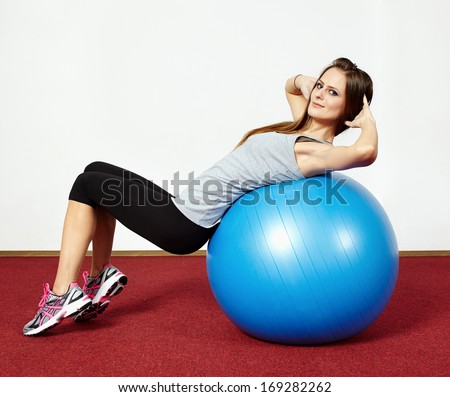 Young Fit Woman Doing Abs Crunches On A Gym Ball