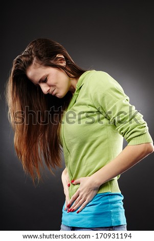 Studio shot of a young woman having a severe abdominal pain over grey background