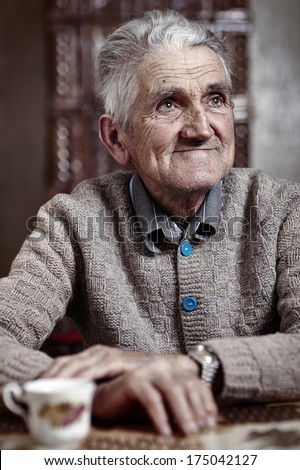Happy old man indoor having his morning cup of coffee
