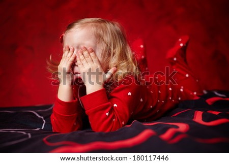 Portrait of a sleepy girl toddler laying in bed rubbing her eyes