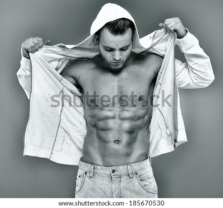 Sexy fashionable young man with unbuttoned hooded shirt showing his six packs
