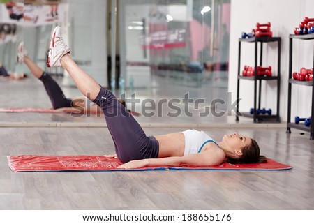 Young woman doing abs workout in a gym on a mat