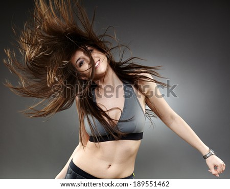 Young woman dancing with her long hair fluttering in motion, isolated on white