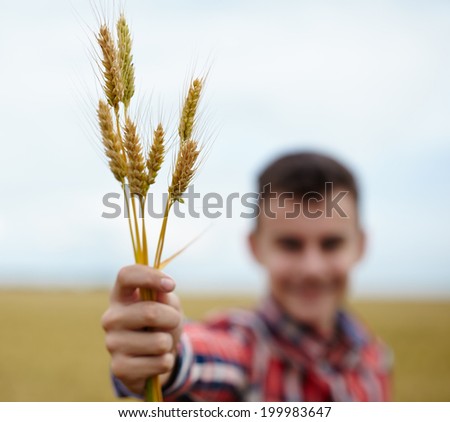 Closeup of a caucasian teenager boy holding a bunch of wheat ears