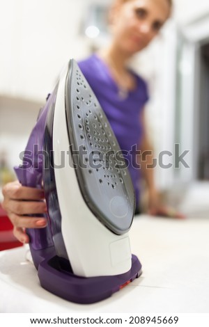 Woman ironing, selective focus on the appliance, indoor scene
