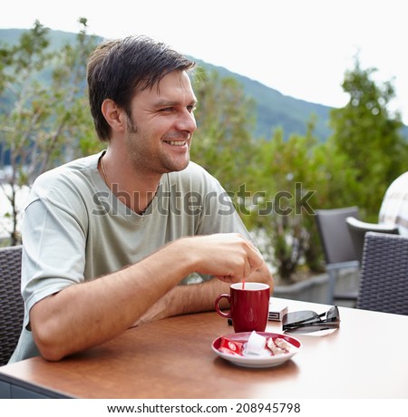 Happy caucasian man having a coffee outdoor on a terrace