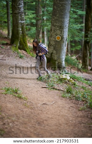 Young hiker woman with backpack on a forest trail in the mountains