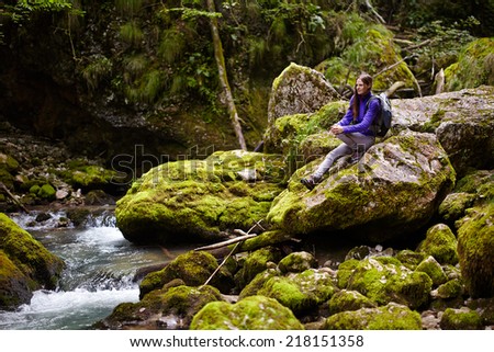 Young hiker woman with backpack resting after crossing the river