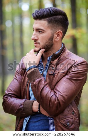 Fashionable young man in leather jacket outdoor in a forest