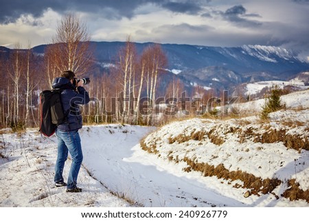 Tourist taking photos of mountains at sunset in a winter evening