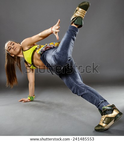 Young girl modern street dancer on gray background, doing dance moves