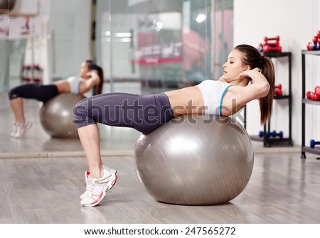 Young woman doing abs crunches with a ball in the gym