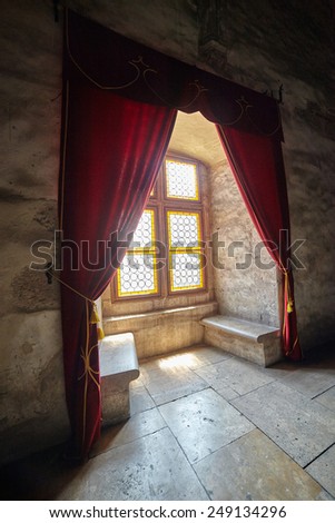 Closeup of a castle window with stained glass and curtains