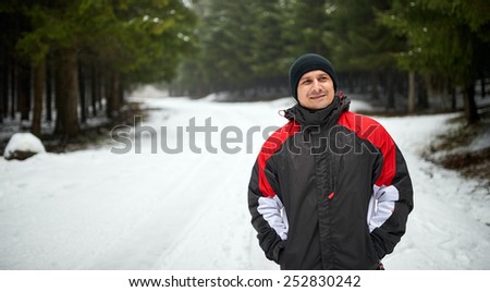 Outdoor winter portrait of a happy young man walking on a mountain trail