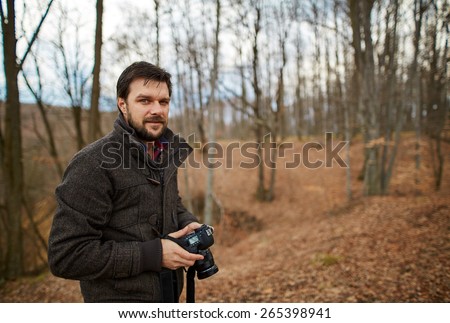 Handsome tourist using digital camera outdoors in a forest on autumn