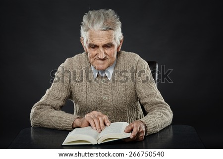 Old man reading a book, studio closeup portrait