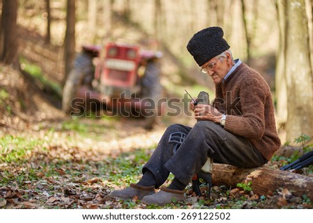 Old farmer doing maintenance work to his chainsaw