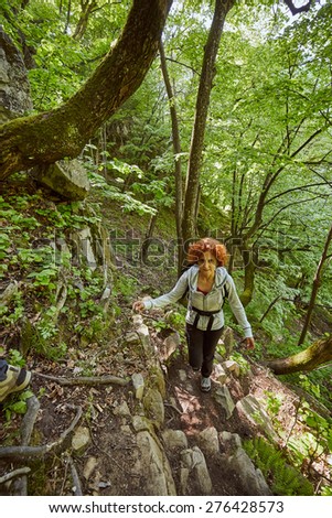 Hiker woman with backpack on a forest trail in the mountains