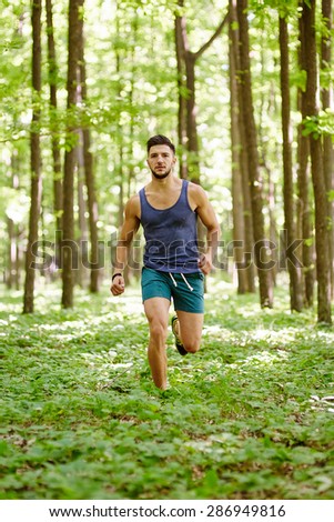 Young and fit runner on a trail run through forest