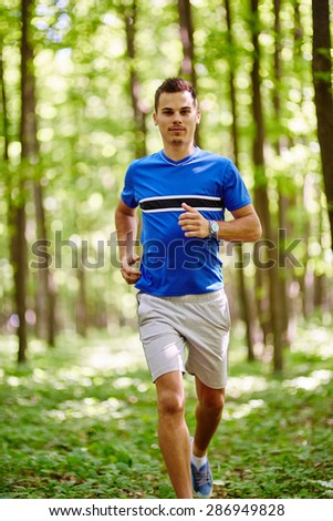 Young and fit runner on a trail run through forest