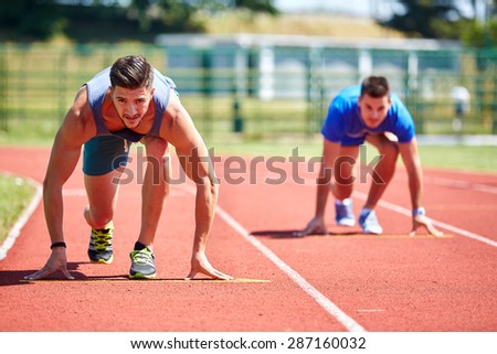 Two friends running on the lines at the stadium in a sunny day