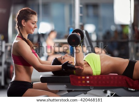 Young woman personal trainer helping with chest workout