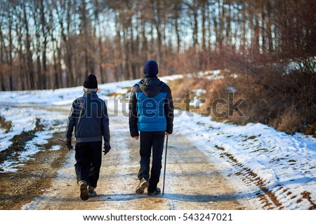 Old farmer and his grandson having a walk in a winter day in the countryside