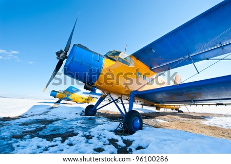 Old airplanes parked on a meadow with snow in a sunny day