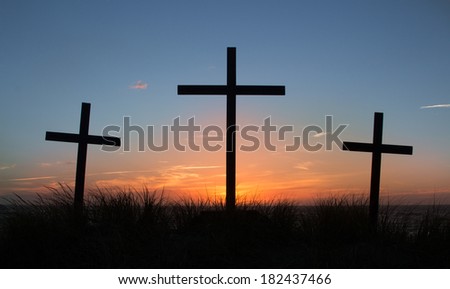 Three crosses with a light clouded sunset behind them Three crosses with a light clouded sunset behind them