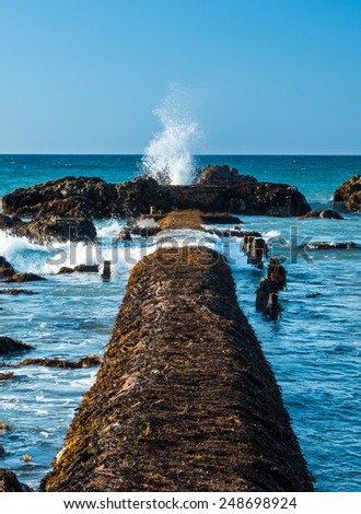 Old pipe line walkway with a rocky splash hole at the end of it.