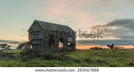 Small old farm house just rotting away, with a morning sky bind it.