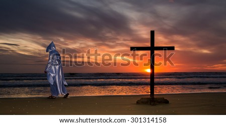 Jesus walking away for a black cross on a beach as the sun goes down.