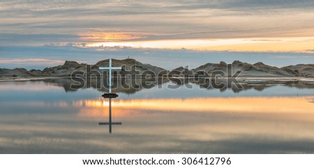 White cross on a flat  lake in a desert.
