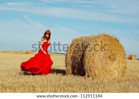 redhead woman in a red dress at village outdoor.