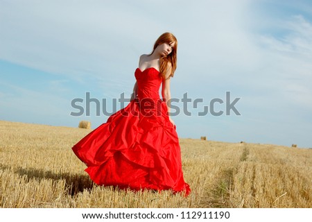 redhead woman in a red dress at village outdoor.