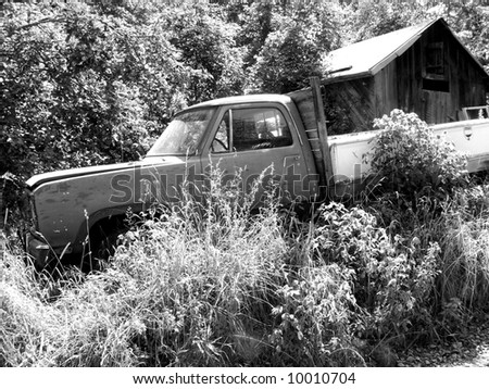 Black and white photo of old rusted truck sitting in weeds along a dirt road in rural W V.