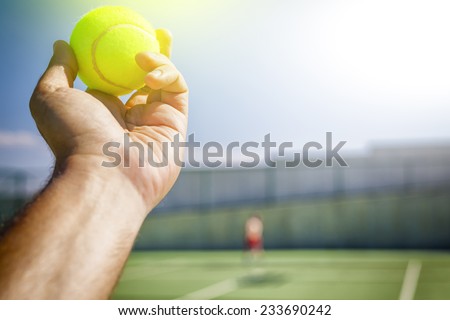 Tennis player holding the ball and getting ready to serve.