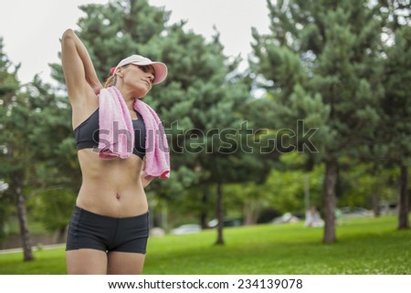 Young woman with towel relaxing in nature after outdoor exercise