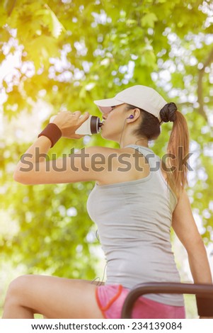 Thirsty young woman drinking water and listening to the music while resting.