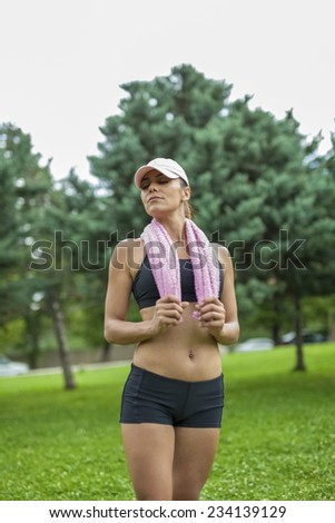 Young woman with towel relaxing in nature after outdoor exercise.