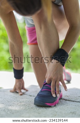 Woman tying her shoe before training in park. Running and jogging exercising concept.