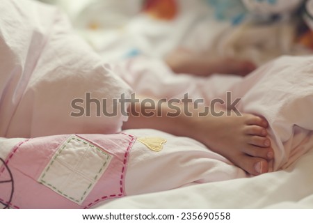 Feet of little sleeping girl in her bed. Comfortable sleep in bed.