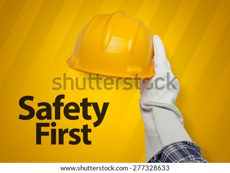 hand holding yellow hardhat. safety first concept.