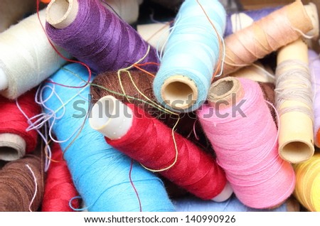 Tangled colorful spools of sewing thread